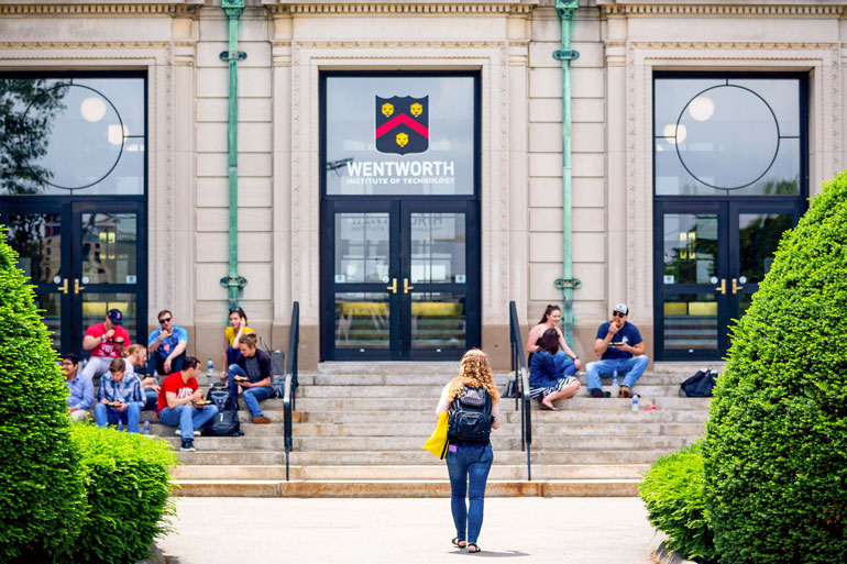 Students walk toward and gather on the front of Wentworth Hall 