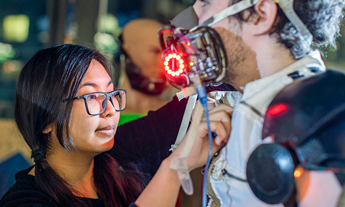 A female student adjust the robotic-like costume modeled by a male student. 