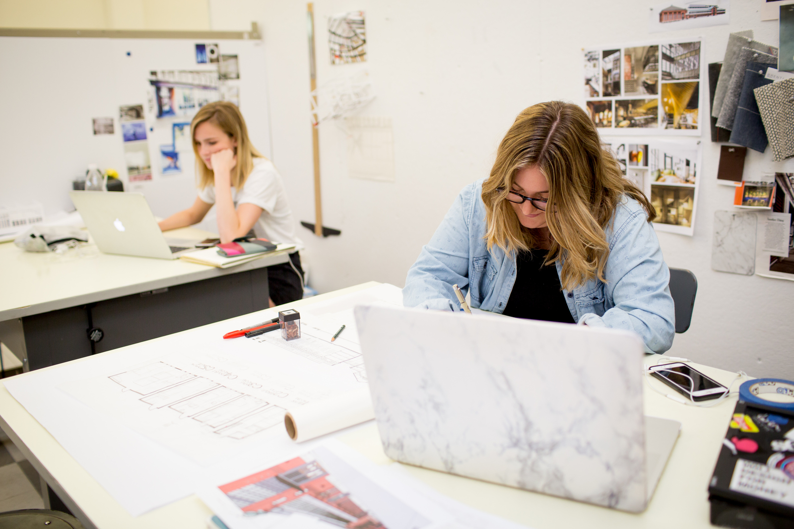 Two students work on laptops in the interior design lab