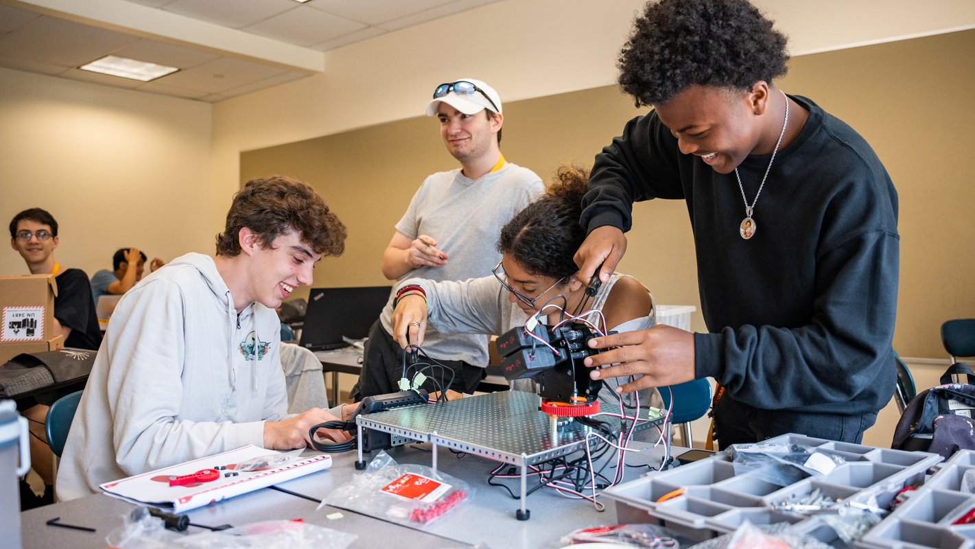 A group of students work on putting together robotics and breadboards in an ImpactLab class