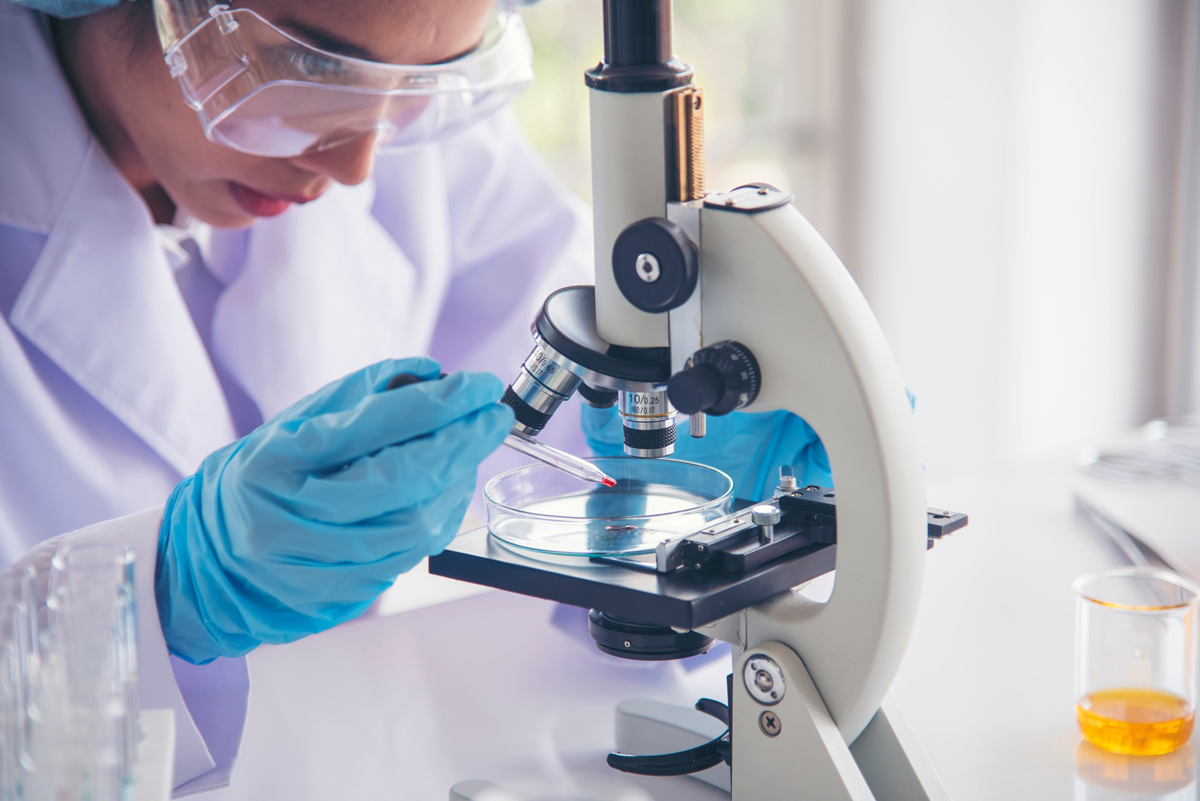 Woman wearing lab coat looking through microscope