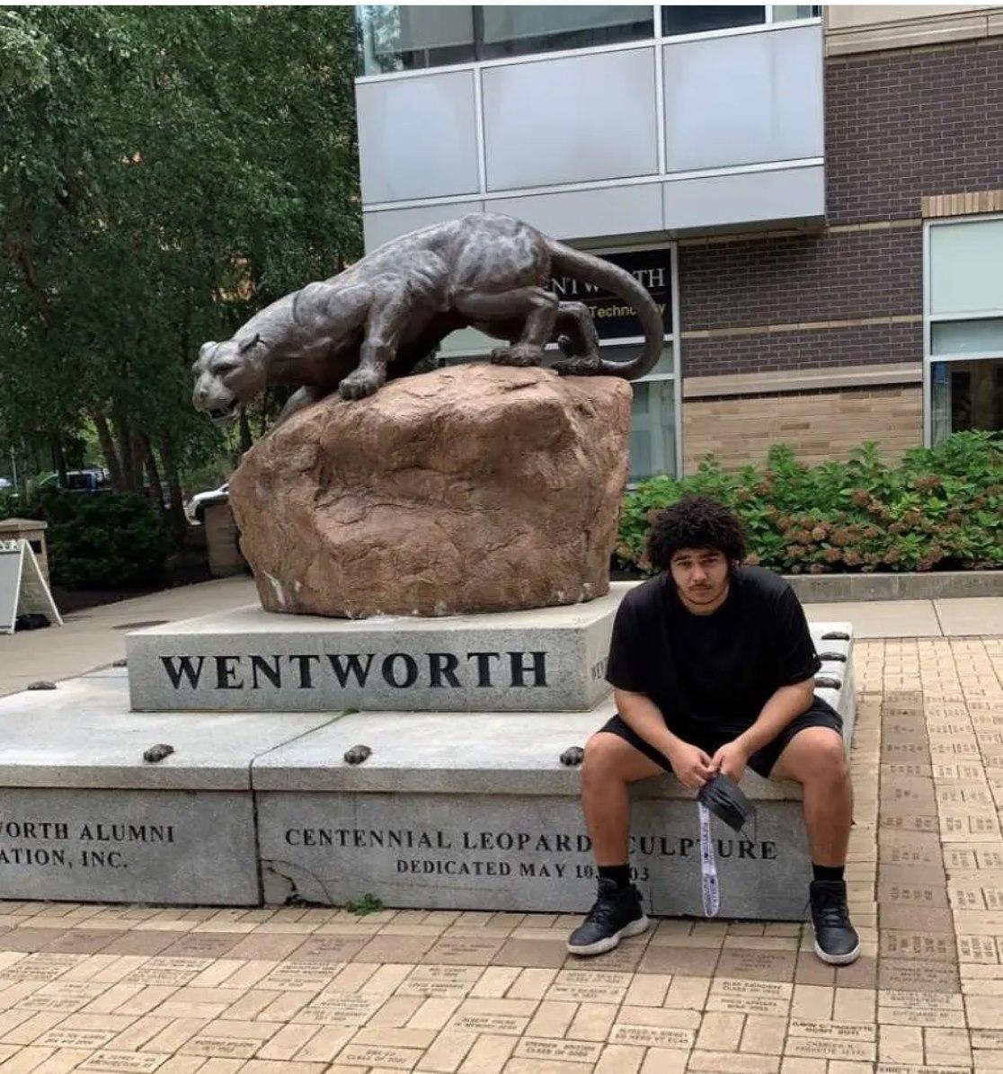 man sits in front of leopard statue