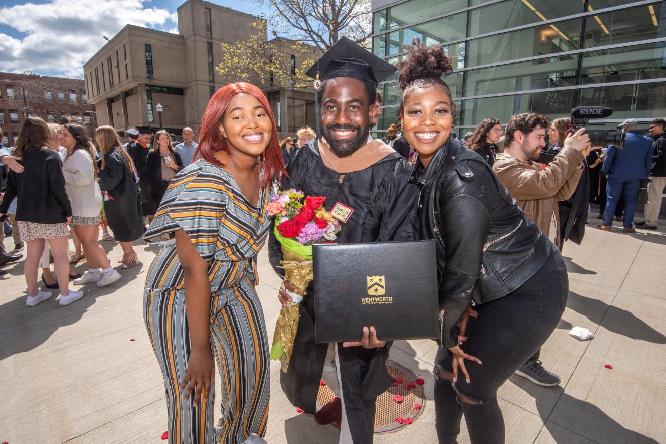 student in graduation robe with family