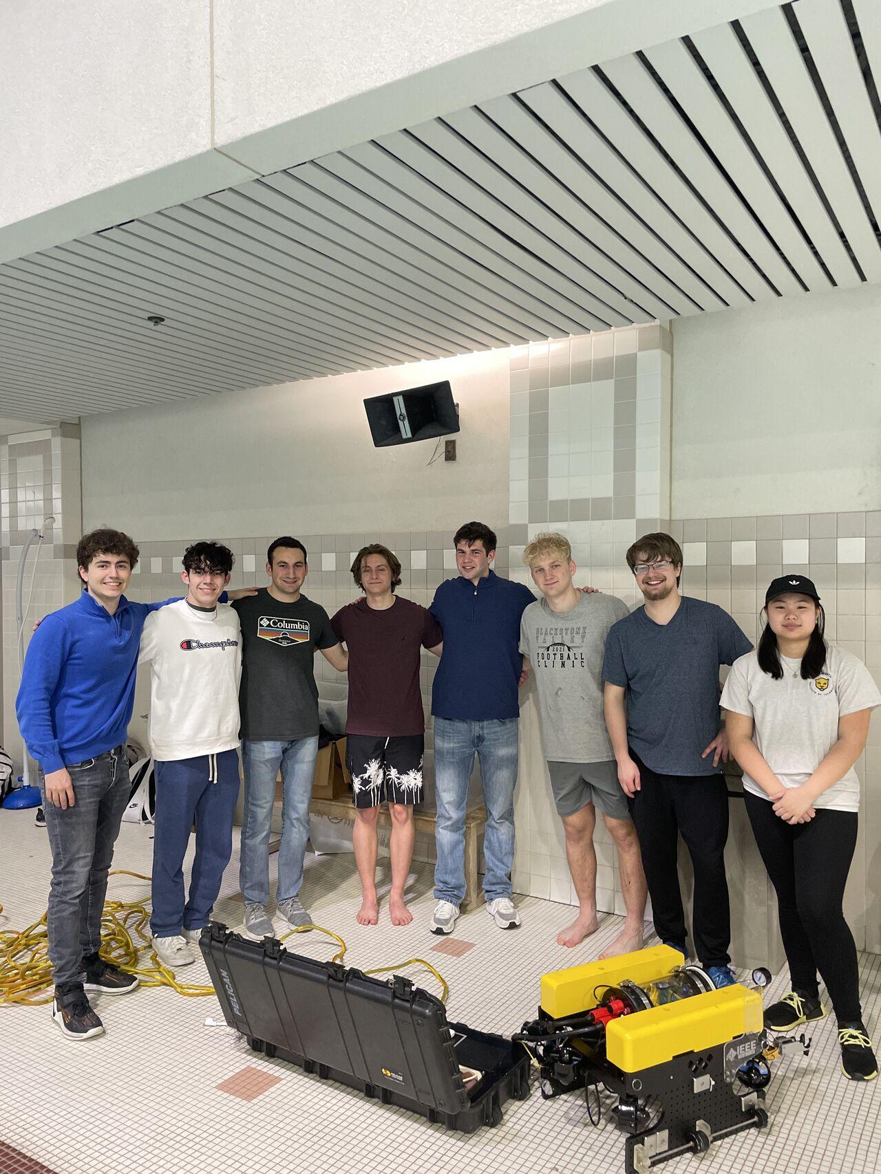 students working on a robot near a swimming pool