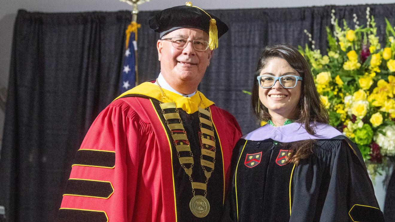 two people in graduation gowns smiling for camera