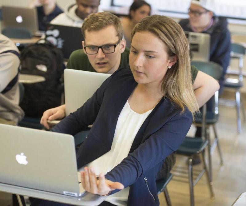 Two students discuss their project together in the classroom