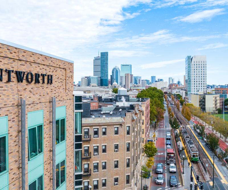 A building on Wentworth's campus with the "Wentworth" name on the side taken by a drone with the city of Boston in the background