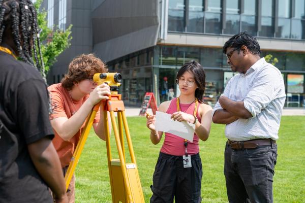 Students use surveying equipment on the quad