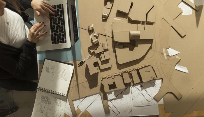 Architectural models and a student working on design files on a laptop