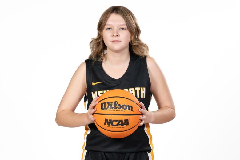 Kailee McPhillips wearing her Wentworth basketball team jersey and holding a basketball