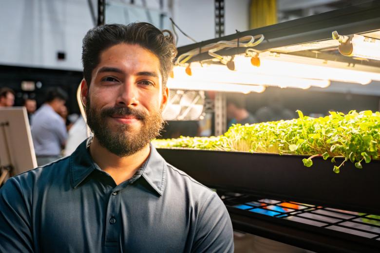 Daniel Mejia-Raminho stands in front of his microgreen capstone project.