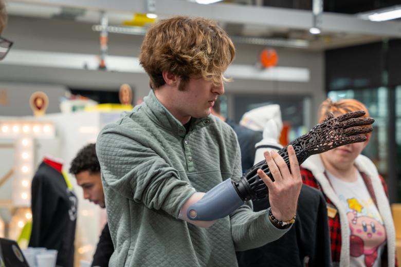 A male student tries on a prosthetic arm as part of the Accelerate maker space entrepreneurship pitch competition.