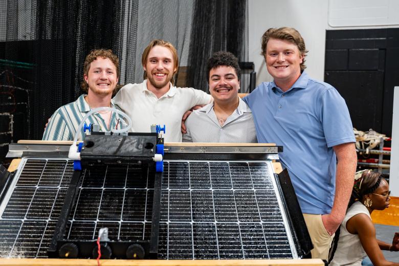 students stand behind a solar panel