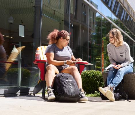 Students sharing notes outside of a building