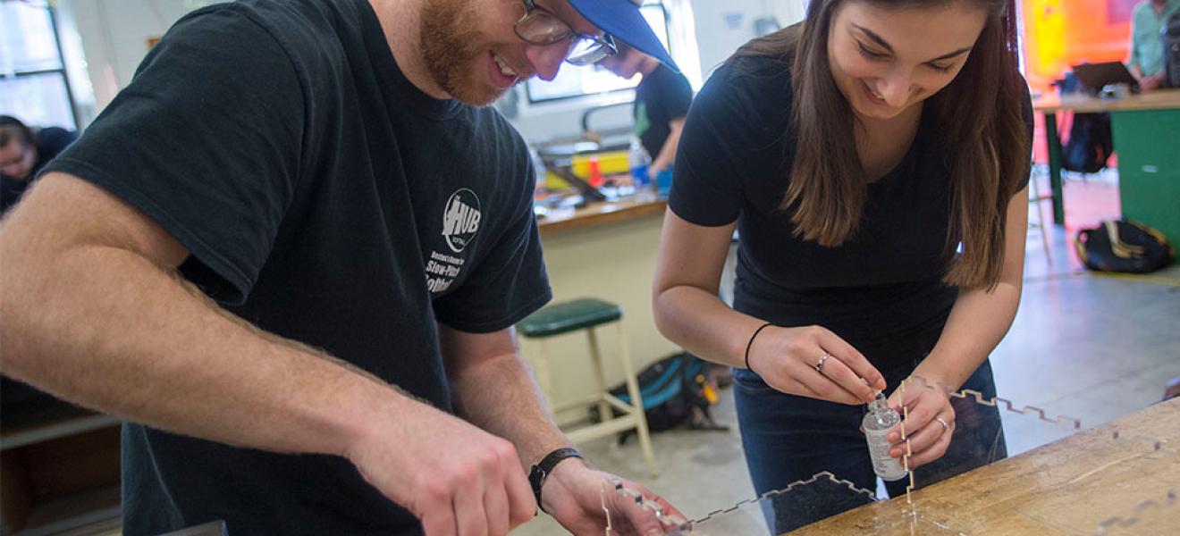 Two students working on engineering project with plexiglass