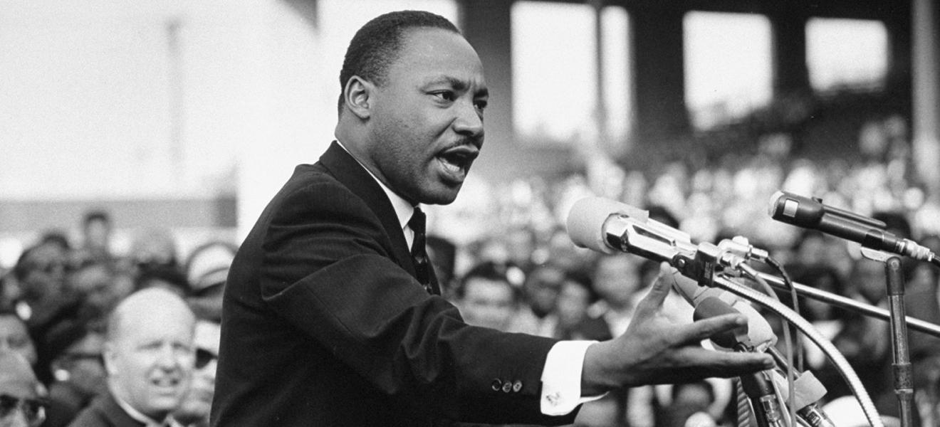 man in front of microphones speaking to a crowd