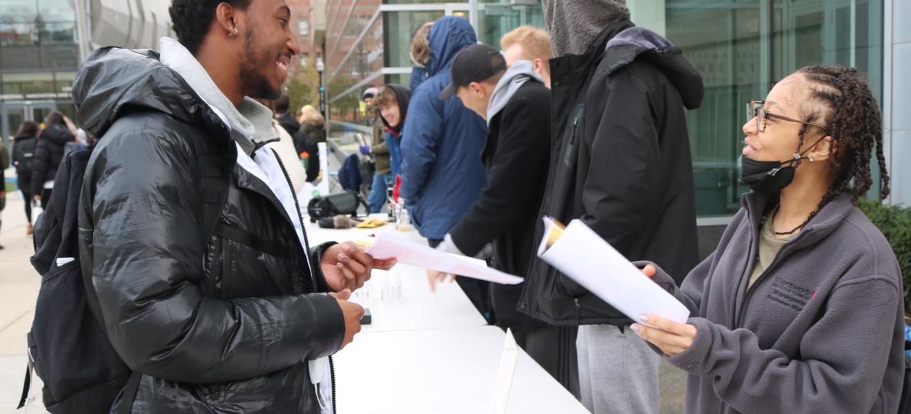 people outside selling items at a table