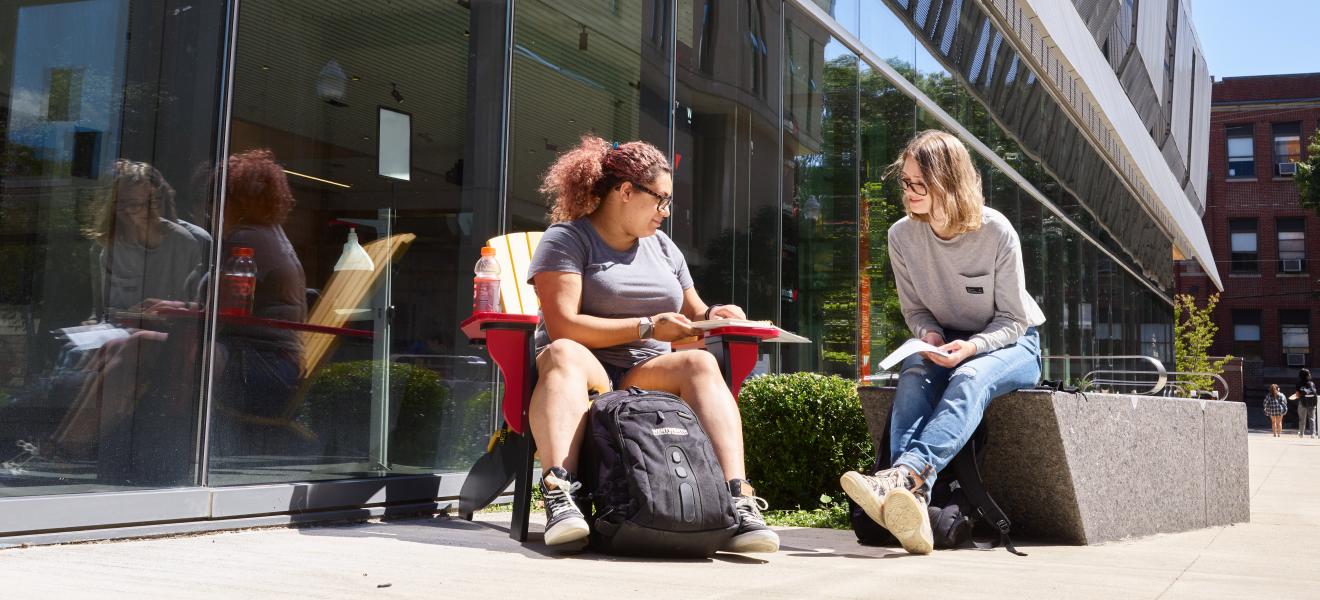 Students sharing notes outside of a building