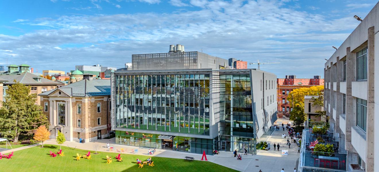 glass building with green space and city buildings surrounding it