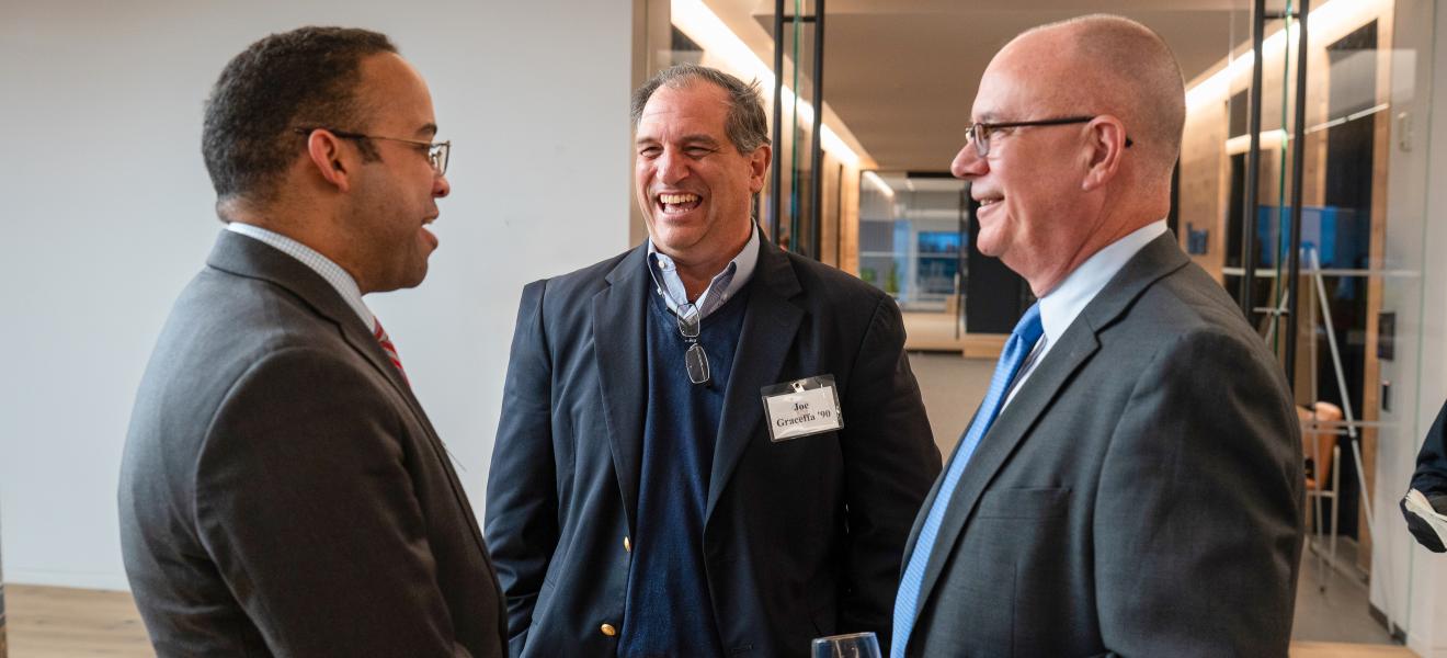 three smiling men having a conversation