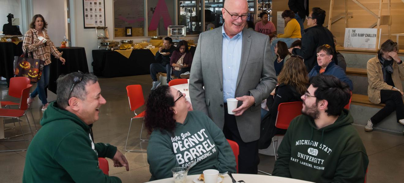 man greeting people seated at a table