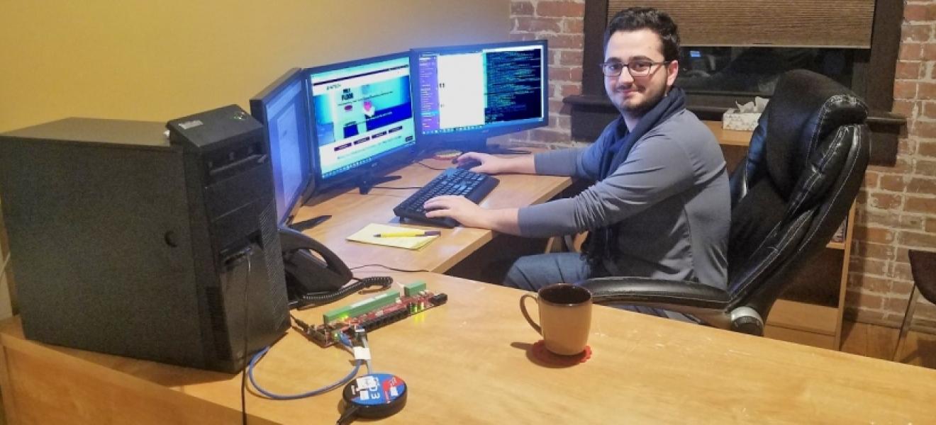 A man sitting in front of a computer screen at a desk